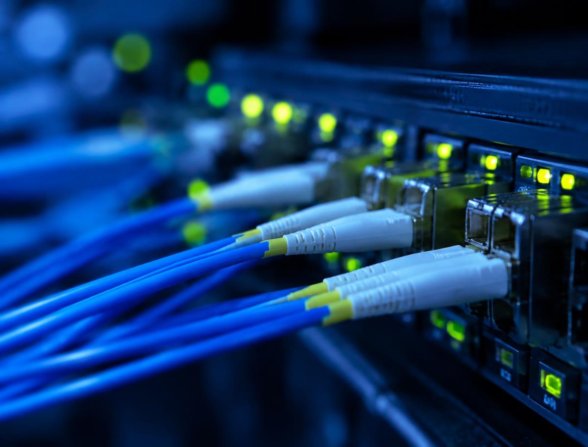 Fiber optic cables connected to a network switch with glowing status lights